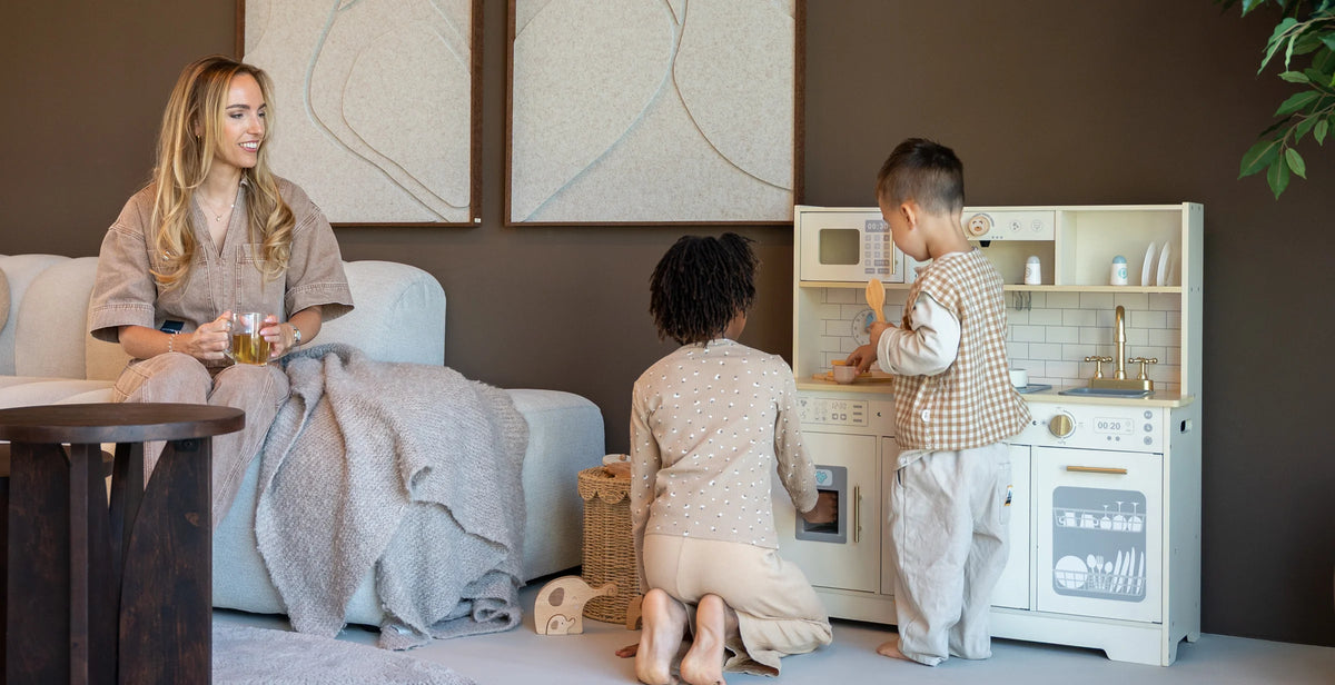 Moeder kijkt toe terwijl twee kinderen spelen met de Baby Doo Luxe houten speelgoedkeuken