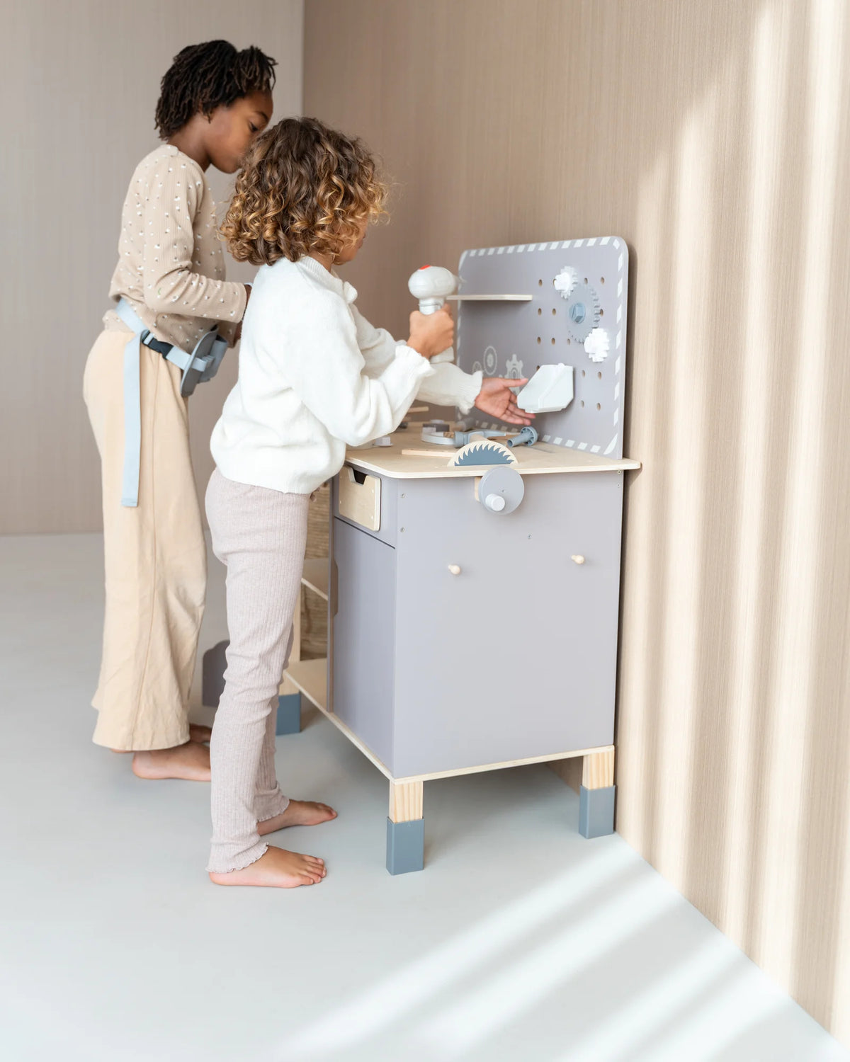 Twee kinderen klussen samen aan de houten speelgoedwerkbank van Baby Doo